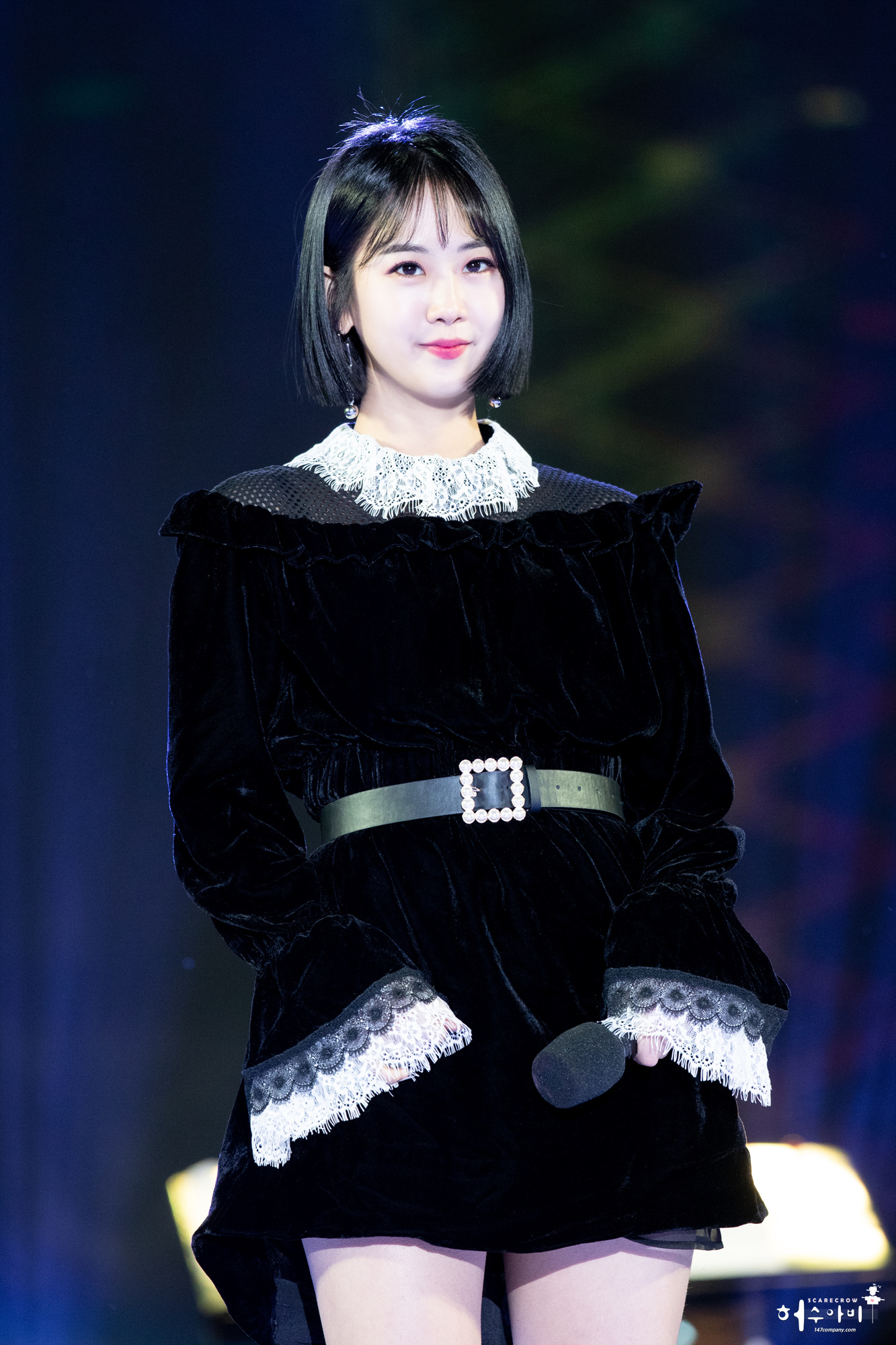푸른 조명 아래 마이크를 내려 들고 서 있는 가수 강혜연