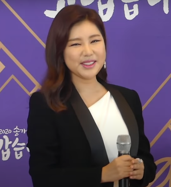 검은 재킷 차림으로 마이크를 들고 미소 짓는 가수 송가인